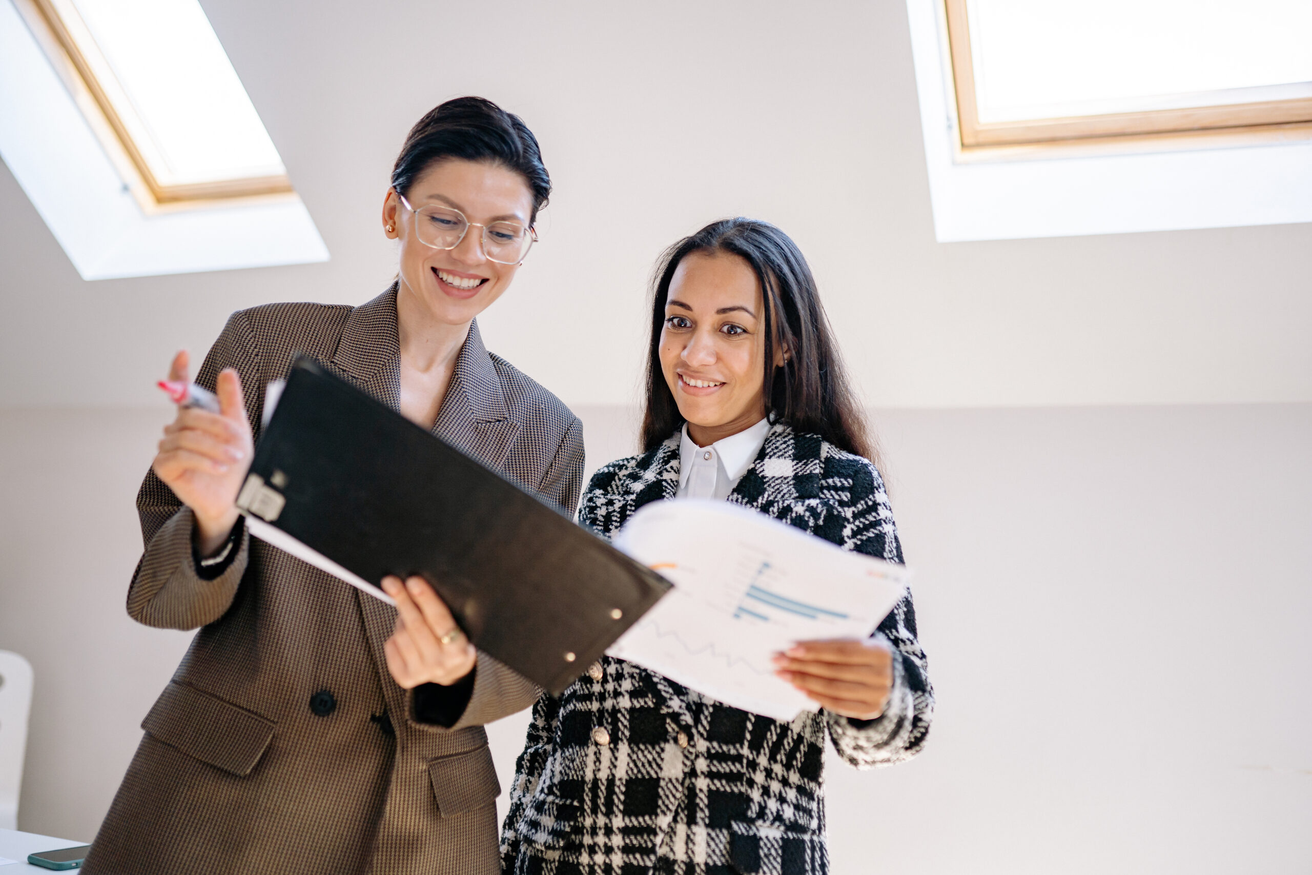 Happy women in corporate attire looking at a document